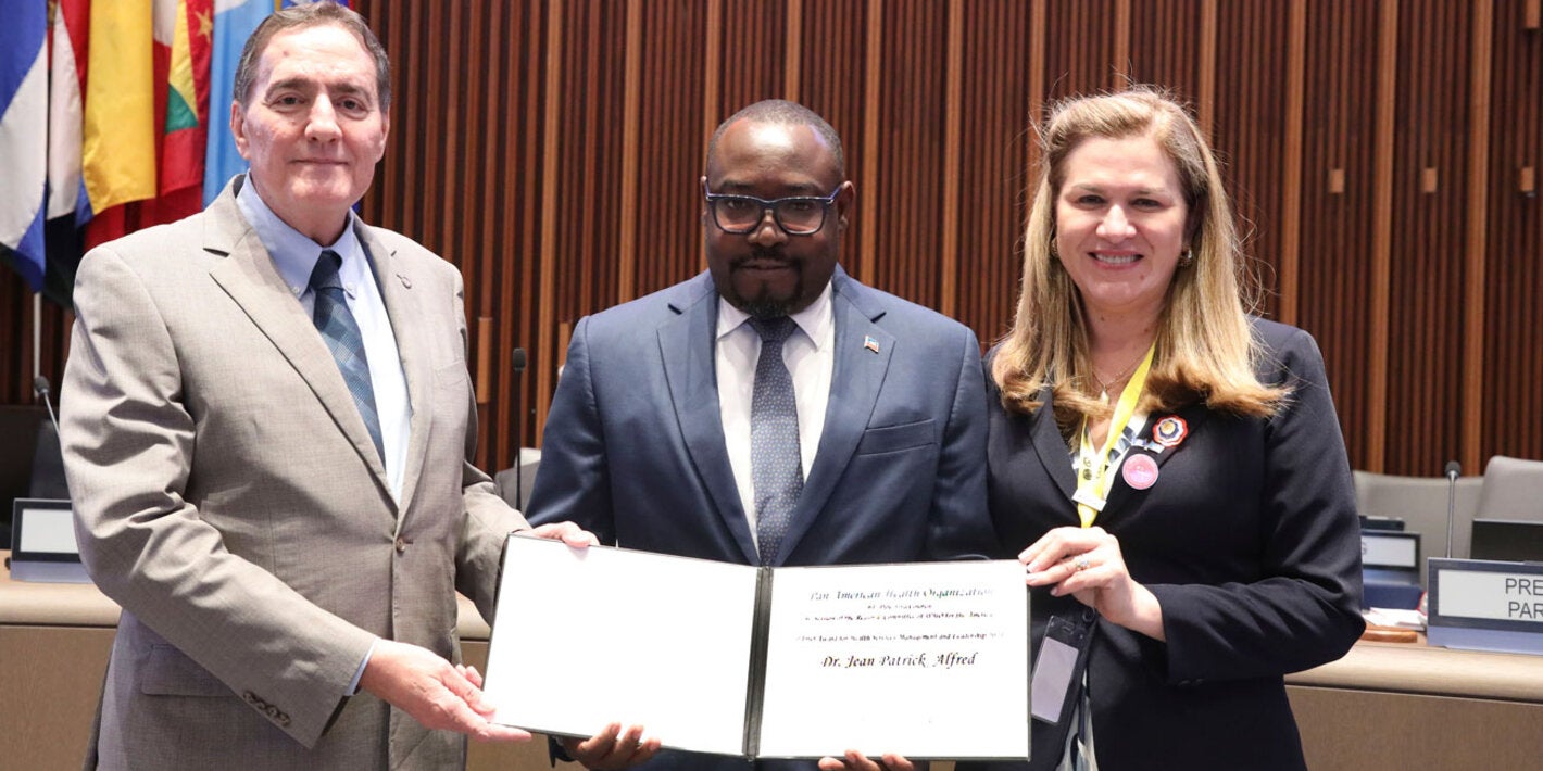 Jean-Patrick Alfred holds the PAHO Award for Management and Leadership. He is standing next to the PAHO Director and the Directing Council president.