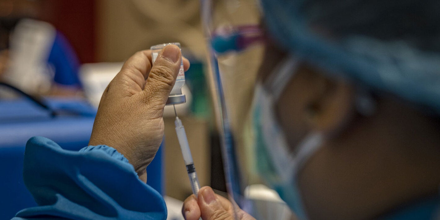 Health worker holds a syringe and a vial