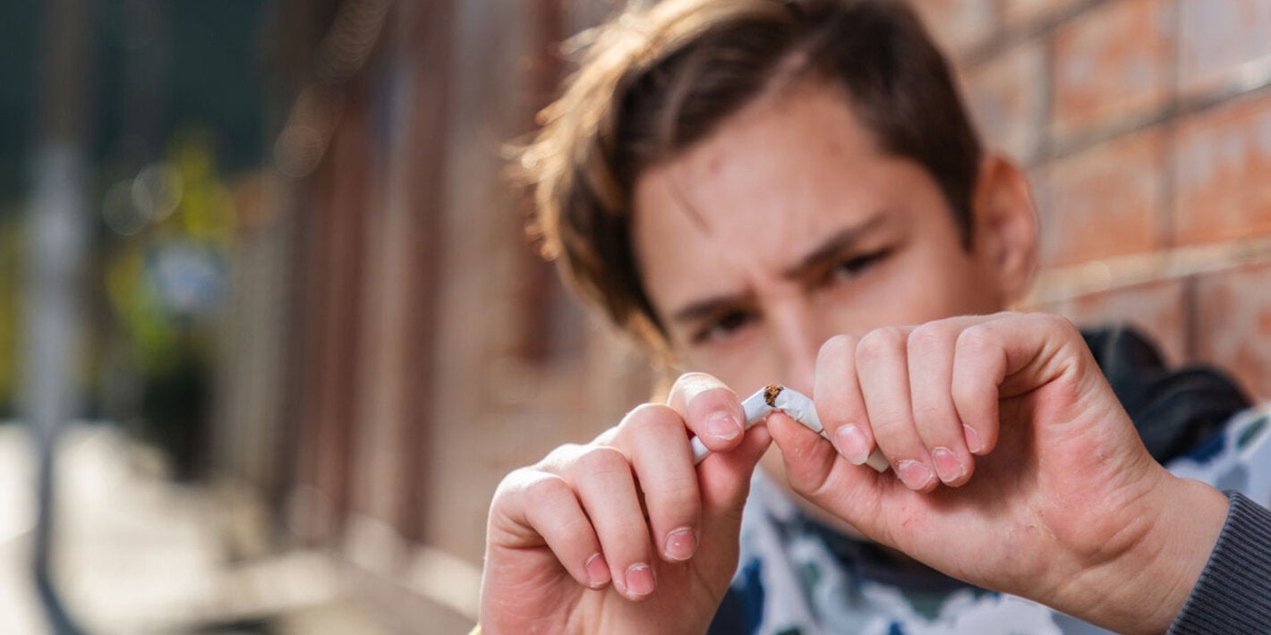 Joven rompiendo un cigarrillo