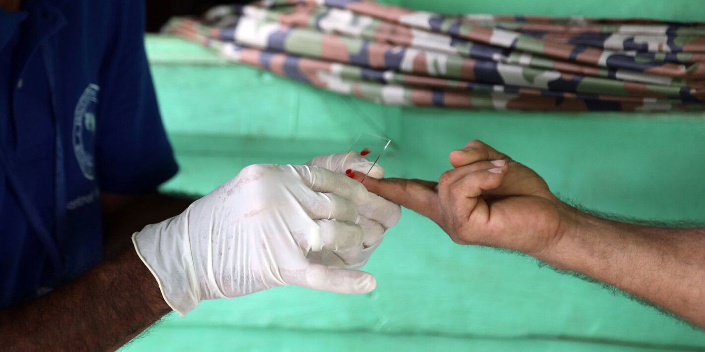 Health worker takes sample from patient to test for the presence of malaria