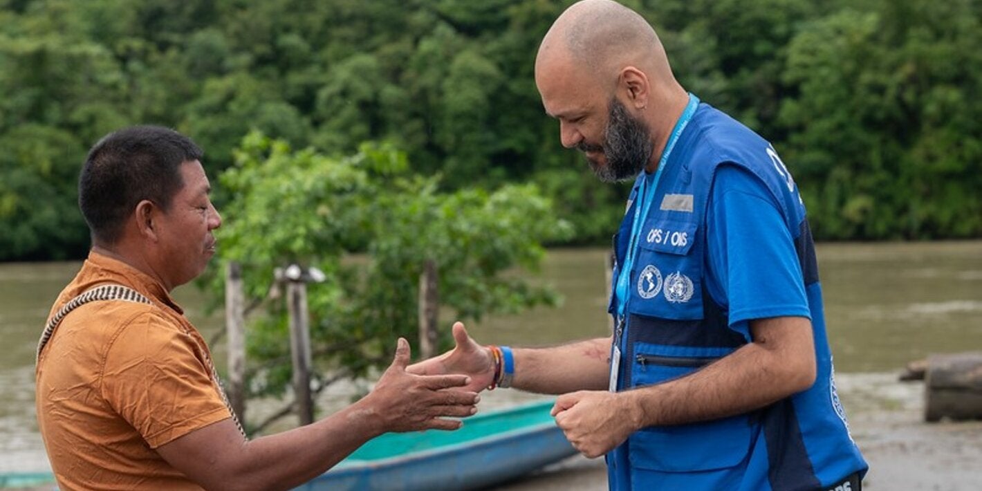 handshake between two men (PAHO personnel and a community leader). Setting: river front