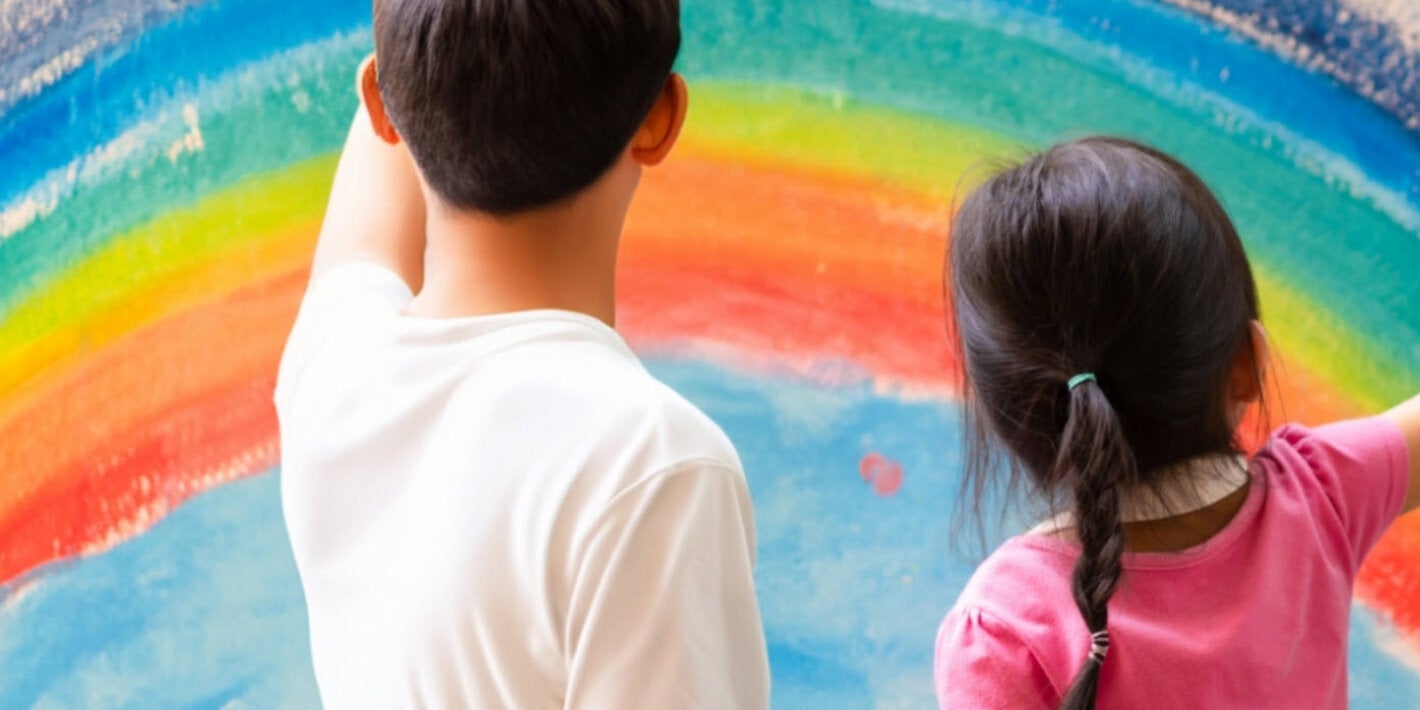 Un niño y una niña mirando una pintura de un arcoíris.