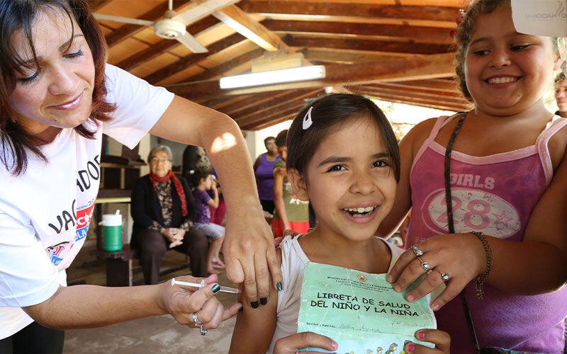 girl getting vaccinated showing immunization card