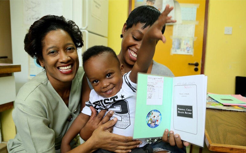 Mom, boy and nurse in health facility showing vaccination card