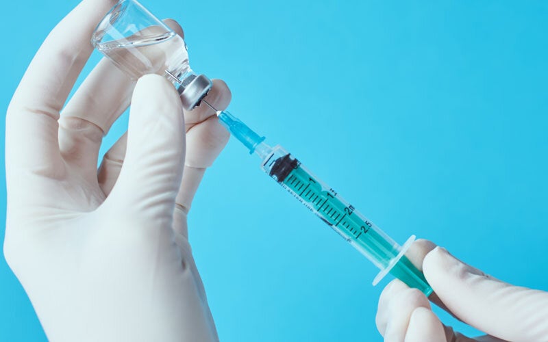 Hand with gloves filling syringe with vaccine