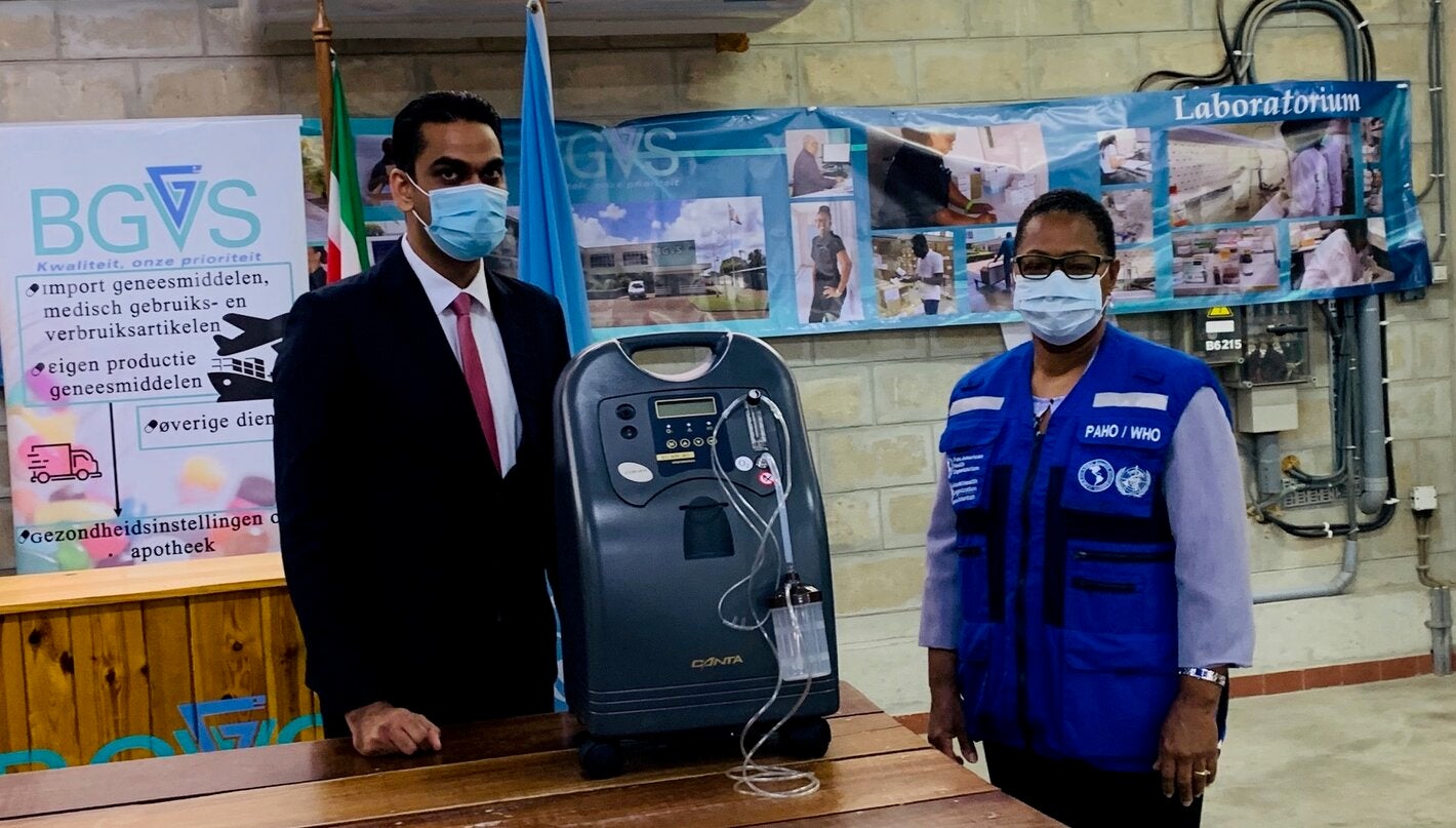 Dr. Lewis Bell, PAHO Representative explains the main features of the donated oxygen concentrators to Minister Ramadhin.