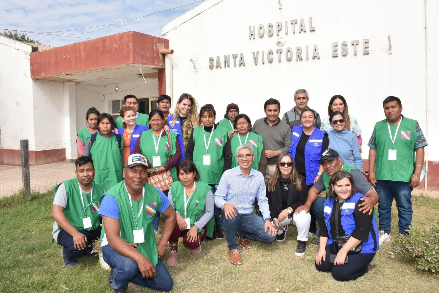 Foto grupal de las personas que participaron de la actividad con el hospital de fondo.