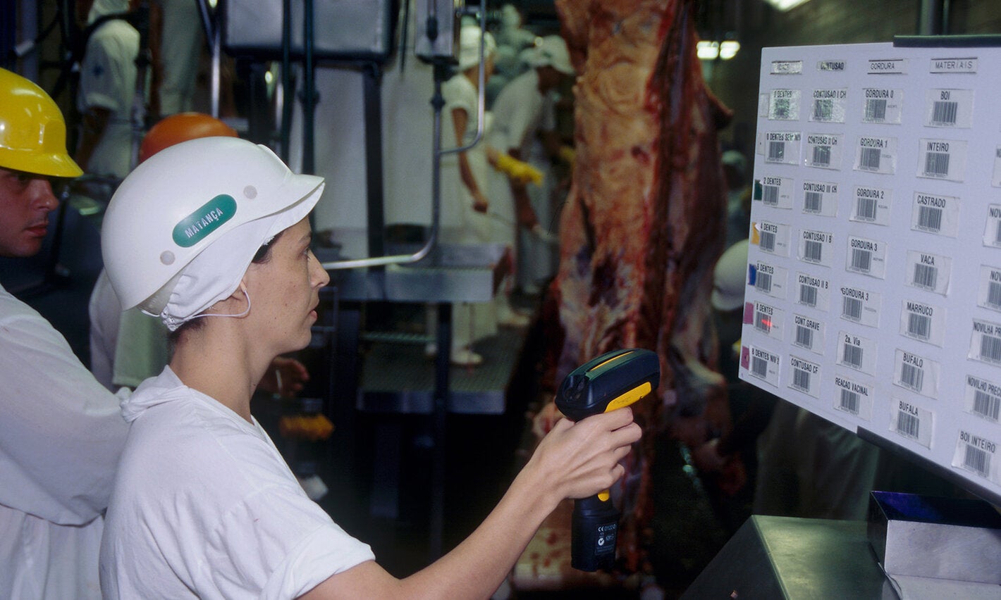 Empleada con casco escaneando códigos de barras en una planta de procesamiento de carne