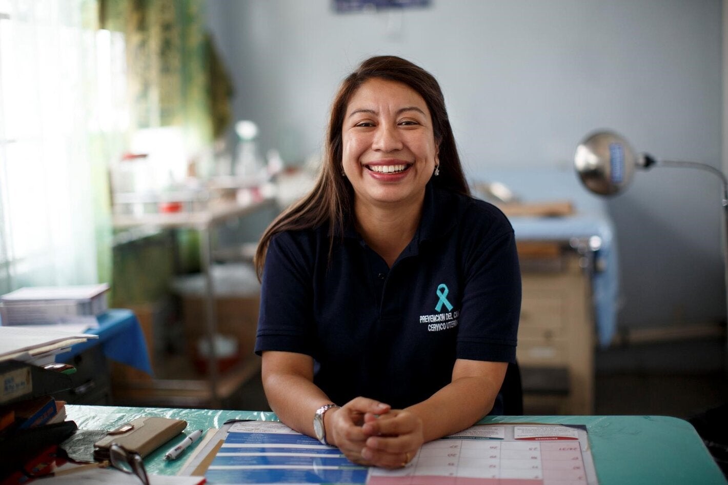 Health professional in her office, wearing a t-shirt with a cervical cancer ribbon