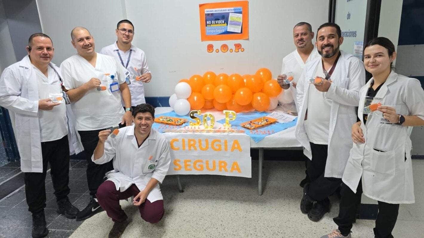 Personal de un centro de salud con distintivos naranja y un stand informativo