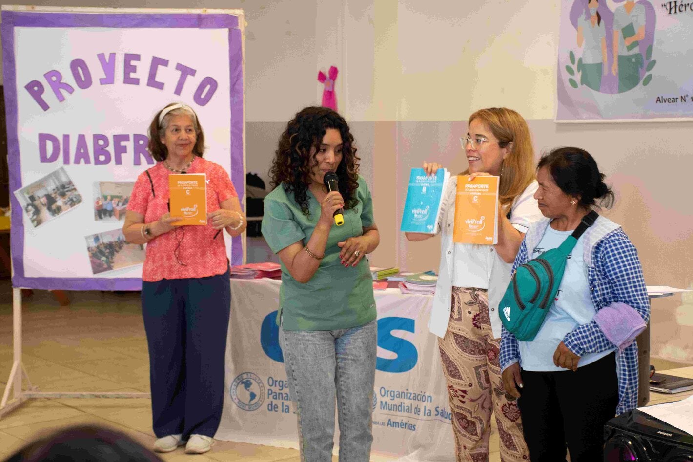 Foto con participantes del programa y del equipo de salud mostrando los distintos pasaportes con sus ejercicios indicados. Hya un cartel hecho a mano que dice proyecto Diabfrail