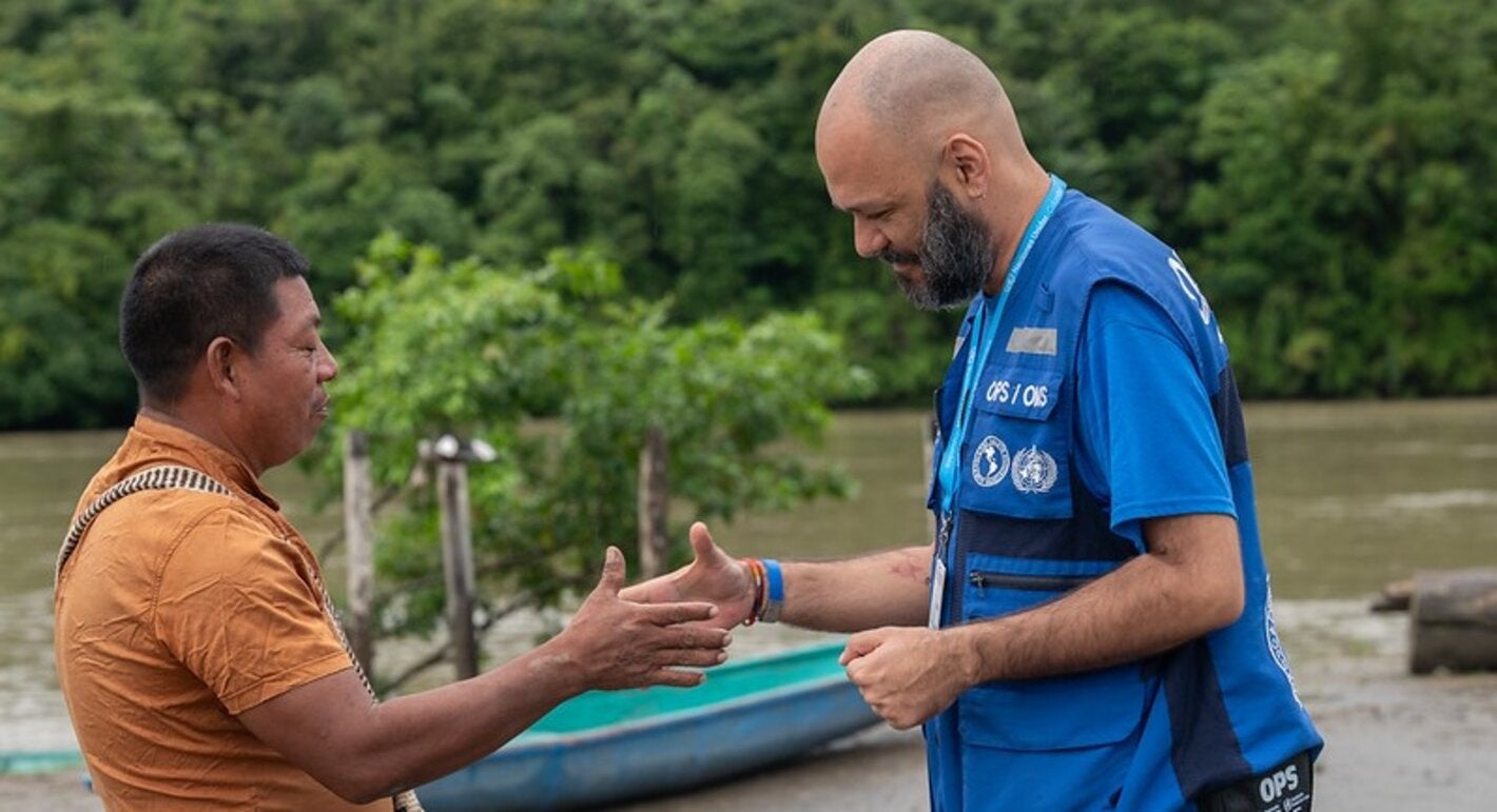 handshake between two men (PAHO personnel and a community leader). Setting: river front