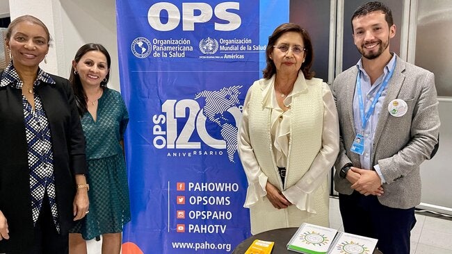 La Dra Gina Tambini, representante de la OPS en Colombia, posa con técnicos de la oficina junto al banner de la organización