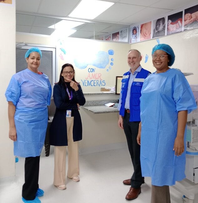 Profesionales de la salud y OPS en hospital, mirando a la cámara