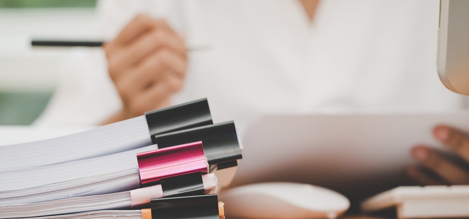 woman reviewing paper stack in foreground