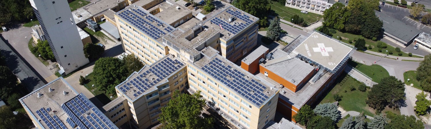 Hospital renovable. Edificios hospitalarios con vista aérea y paneles solares en el techo de una bonita zona verde.