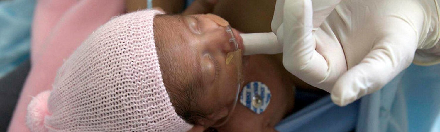 premature baby sucking on a gloved finger