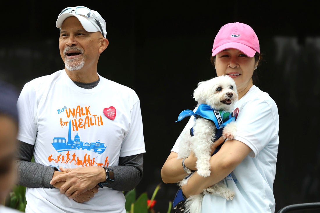 A couple who is participating at The Walk for Health hold their white dog.